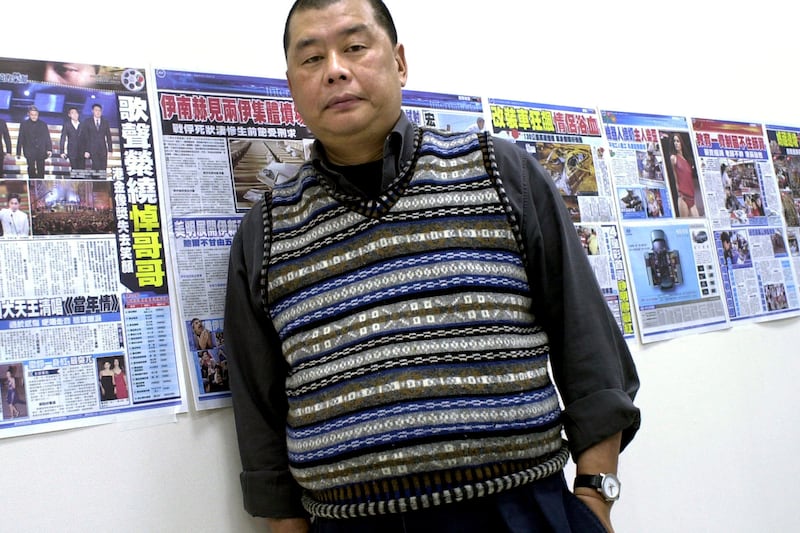 Jimmy Lai, owner of the Hong Kong newspaper Apple Daily, poses next to dry runs of a soon to be launched Taiwanese newspaper taped to his office wall, April 7, 2003, in Taipei.
